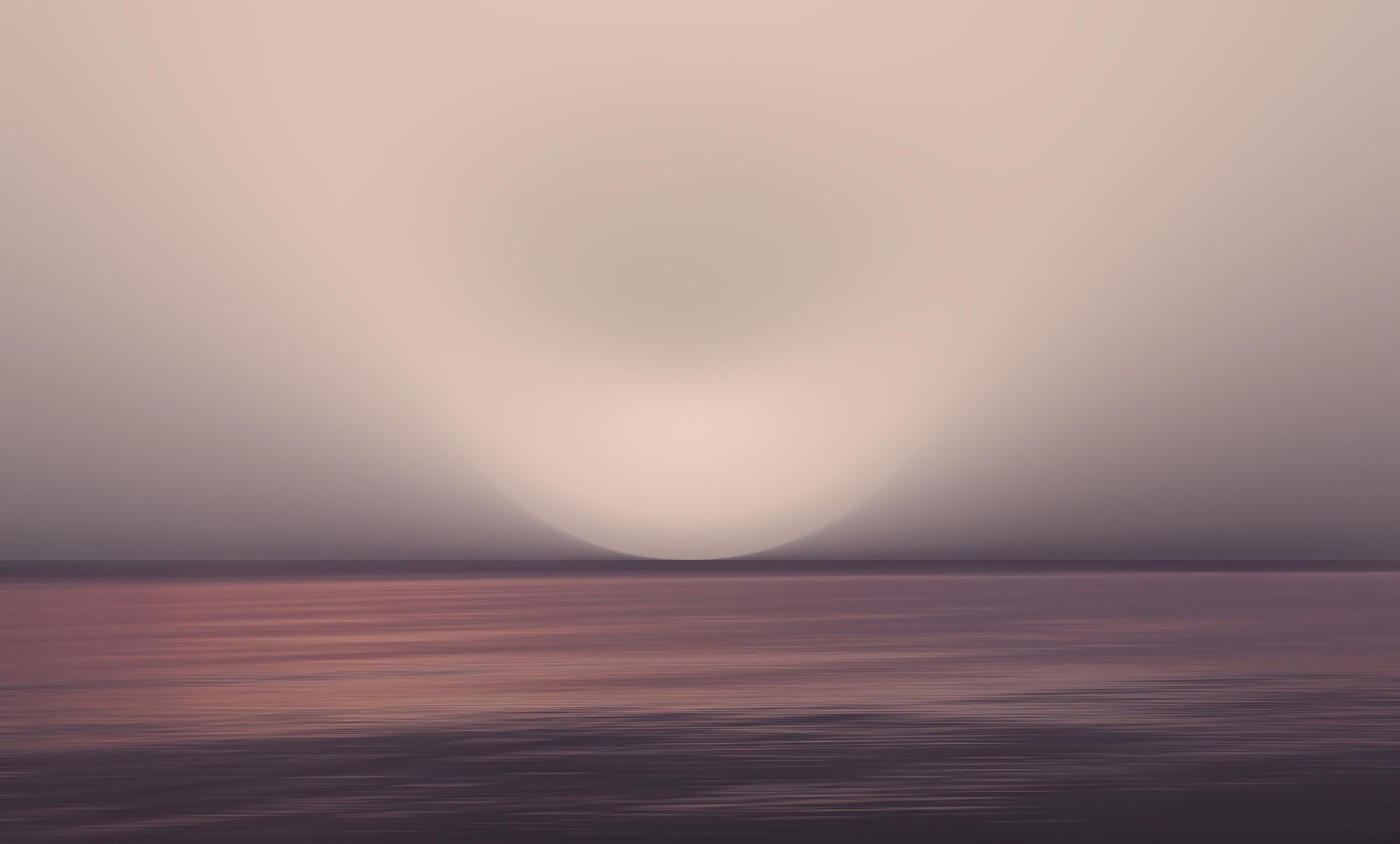 A misted horizon at dusk over still water